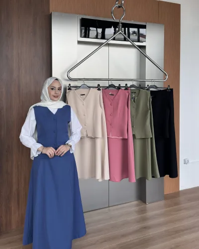 Model in the royal blue buttoned vest dress beside a rack showing the beige, rose, khaki and black colourways