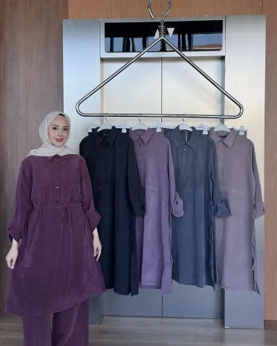 Model in the plum linen tunic set beside a rack showing the black, lilac, grey and mauve colourways