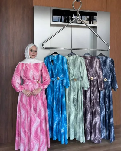 Model in the pink wave print dress beside a rack showing the blue, mint and lilac colourways